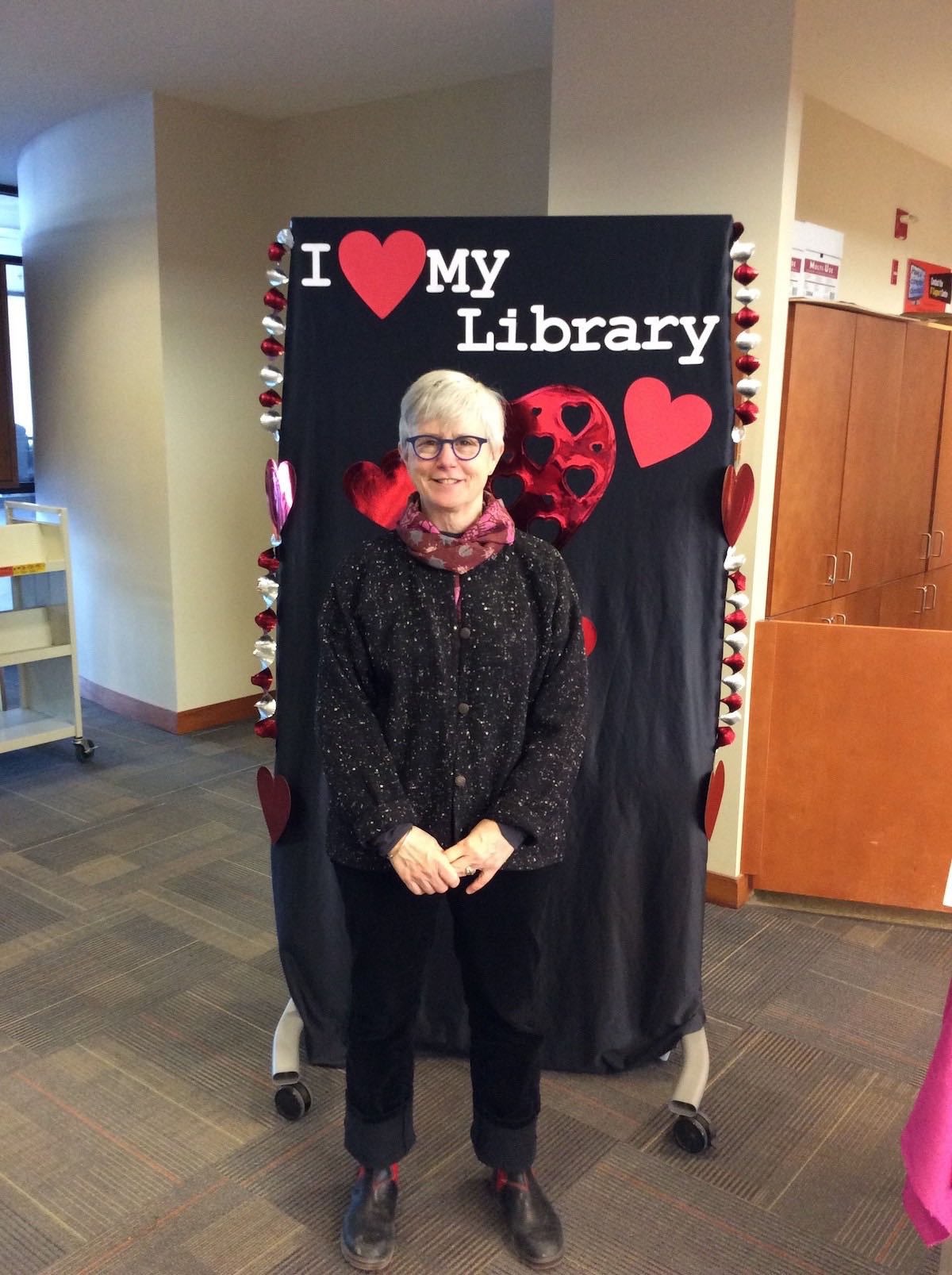 Associate University Librarian for Teaching, Learning and Research Colleen Murphy stands in front of the I love my library backdrop, holding her hands in front of herself and smiling